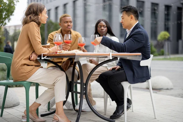 Bir grup iş adamı açık kafede kutlama yapıyor.