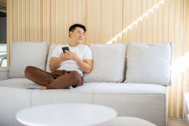 Akıllı telefon kullanan ve eve bakan bir adam.