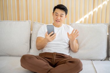 Asyalı adam akıllı telefondan video görüşmesi yapıyor.