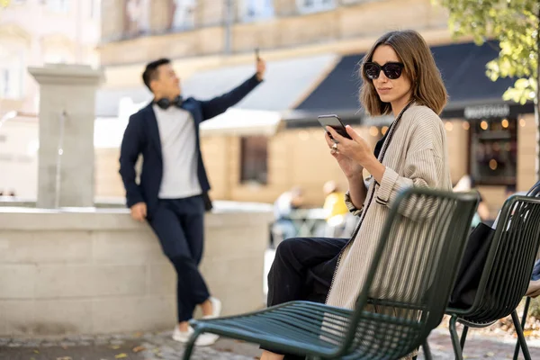Γυναίκα και άνθρωπος που χρησιμοποιούν smartphones στην περιοχή της πόλης — Φωτογραφία Αρχείου