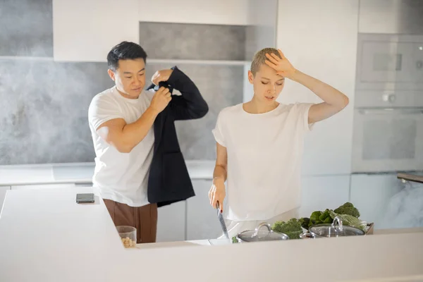 Müde Frau kocht Salat in Küche neben Mann — Stockfoto