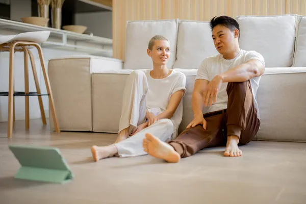 Paar zitten en praten op de vloer met digitale tablet — Stockfoto