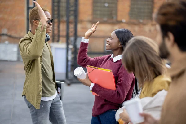 Black girl and guy hold hands near their friends — Stock Photo, Image