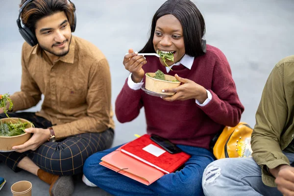 アスファルトで昼食中にサラダを食べる学生 — ストック写真