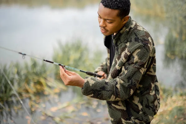 Hombre caña de pescar correcta en la pesca en la costa del lago —  Fotos de Stock
