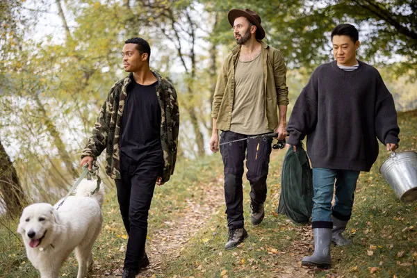 Los hombres caminan con perro y equipo de pesca en la naturaleza — Foto de Stock