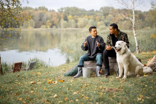Hommes amis parler près de chien sur la côte de la rivière — Photo
