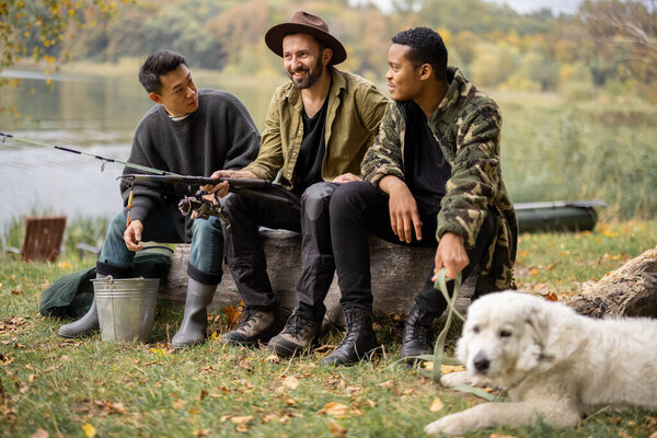 Multiracial male friends rest and talk in nature