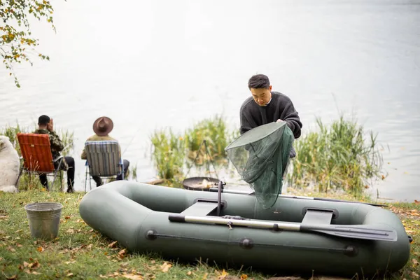 Mann nimmt Fischernetz, während seine Freunde fischen — Stockfoto