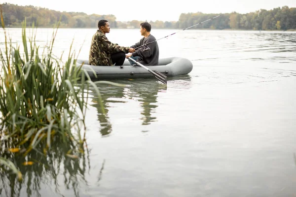 Erkek arkadaşlar nehirde kauçuk teknede balık tutuyor. — Stok fotoğraf