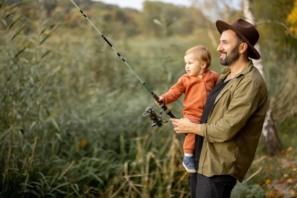 Uomo pesca con il piccolo figlio sulla costa del lago — Foto Stock