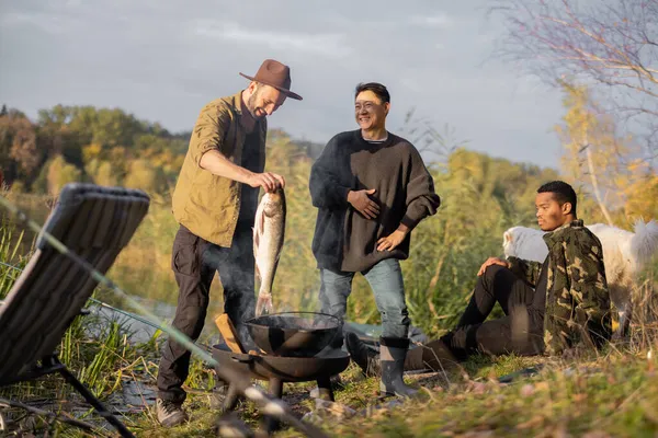 Mann legt großen Fisch zum Kochen in die Nähe von Freunden — Stockfoto
