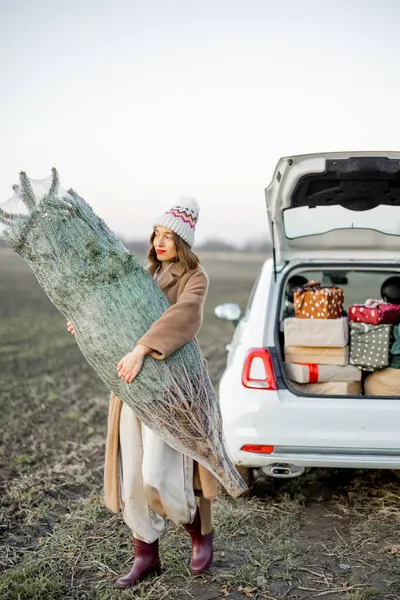 Femme allant avec arbre de Noël près de la voiture sur la nature — Photo