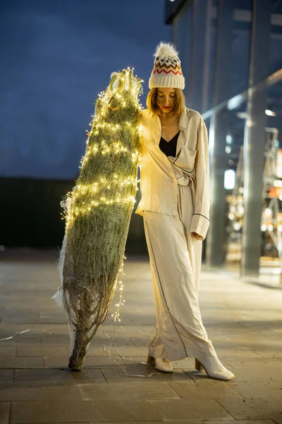Mujer con árbol de Navidad iluminado cerca del centro comercial —  Fotos de Stock