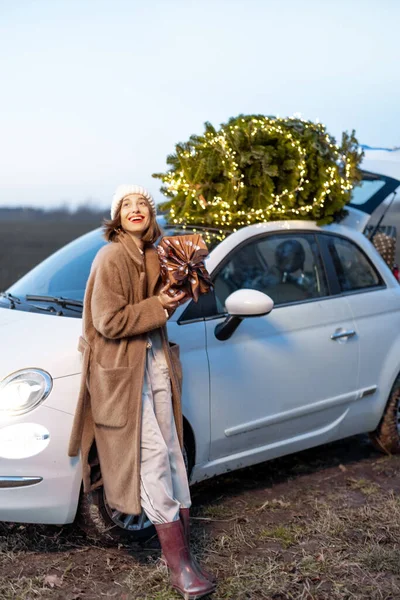 Femme heureuse avec des cadeaux et un arbre de Noël à l'extérieur — Photo