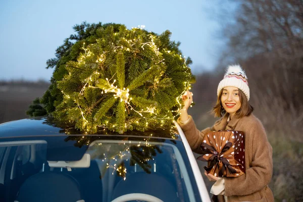 Femme heureuse avec des cadeaux et un arbre de Noël à l'extérieur — Photo