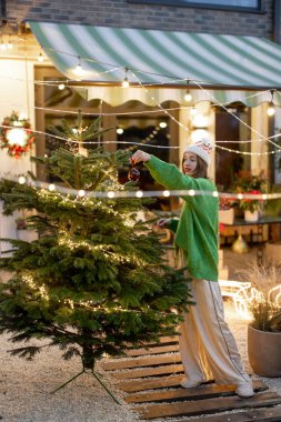 Arka bahçede Noel ağacı süsleyen kadın.
