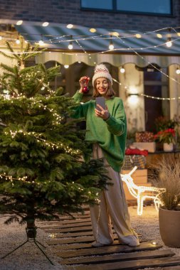 Arka bahçede Noel ağacı süsleyen kadın.