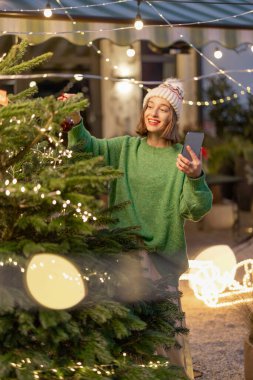 Arka bahçede Noel ağacı süsleyen kadın.