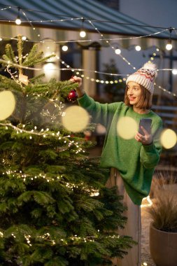 Arka bahçede Noel ağacı süsleyen kadın.