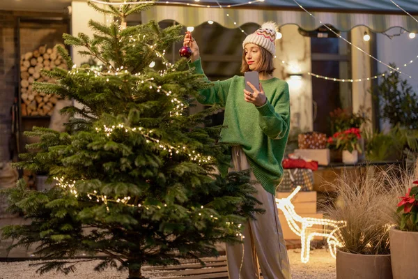 Frau schmückt Weihnachtsbaum im Hinterhof — Stockfoto