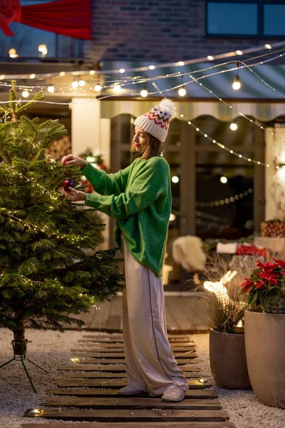 Mujer decorando árbol de Navidad en el patio trasero — Foto de Stock
