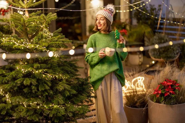 Mujer con galleta y taza en Año Nuevo decorado patio trasero —  Fotos de Stock