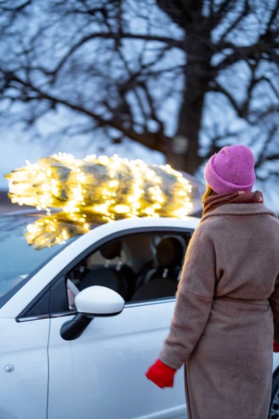 Mulher carrega árvore de Natal de carro — Fotografia de Stock