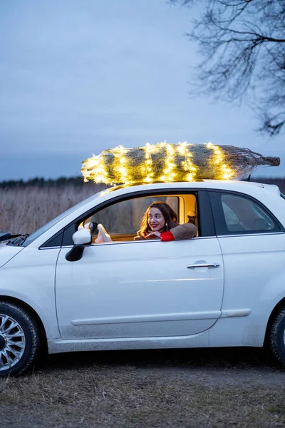 Mulher carrega árvore de Natal de carro — Fotografia de Stock
