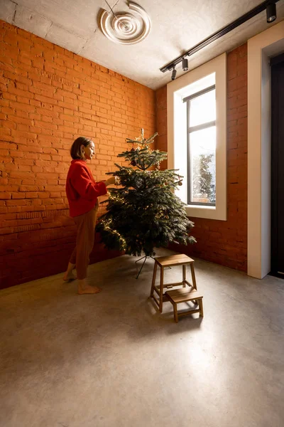 Kvinne som pynter juletreet hjemme – stockfoto