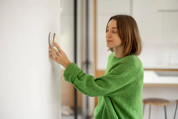 Mujer que controla la temperatura con un termostato inteligente en un apartamento moderno. — Foto de Stock