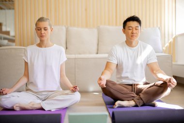 Çiftler yoga yaparken birbirlerine bakarlar.