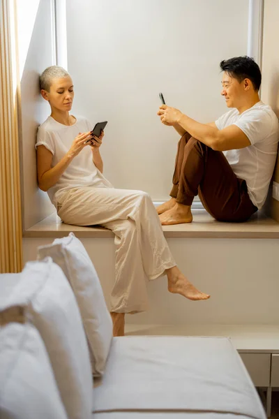 Couple with smartphones look at each at home — Stock Photo, Image