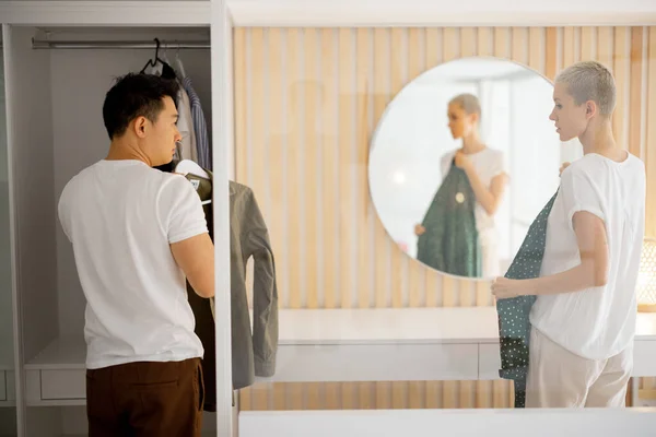Muž si vybrat oblečení a dívka vzhled šaty v zrcadle — Stock fotografie