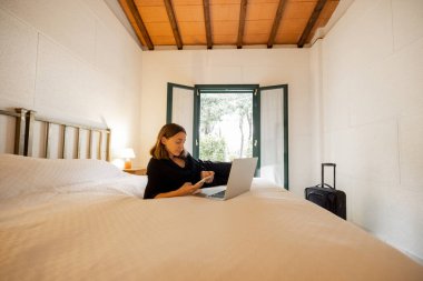 Bir kadın otel odasında yatıp alet kullanıyor.