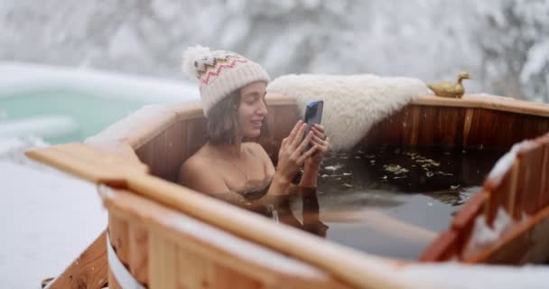 Жінка відпочиває в гарячій ванні в засніжених горах — стокове відео