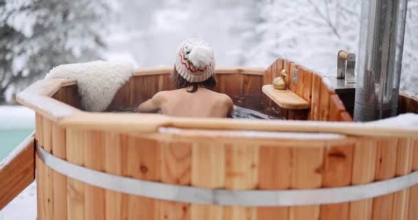 Жінка відпочиває в гарячій ванні в засніжених горах — стокове відео