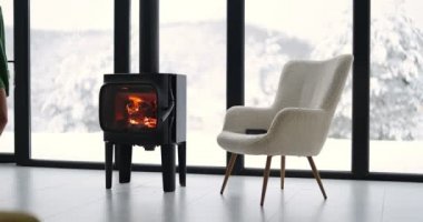 Woman sits on chair by the fireplace at house on nature