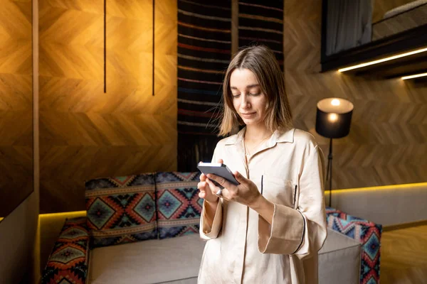 Mujer usando teléfono en apartamento moderno — Foto de Stock