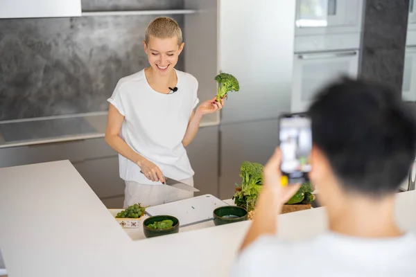 Erkek, akıllı telefondaki kadının salata pişirme videosunu çeker. — Stok fotoğraf