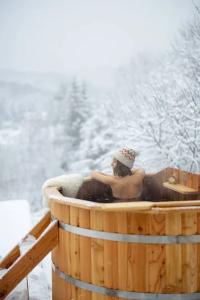 Kobieta relaksująca się w gorącej kąpieli w śnieżnych górach — Zdjęcie stockowe