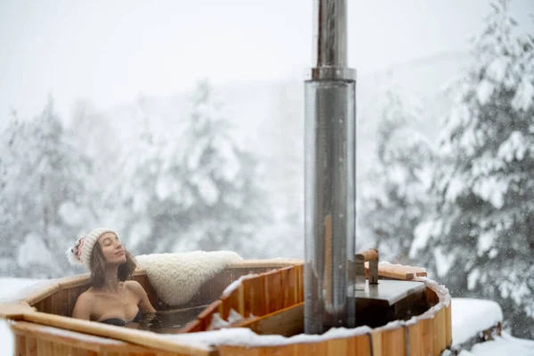 Woman relaxing in hot bath at snowy mountains — Stock Photo, Image