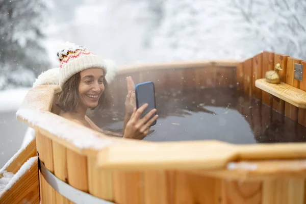 Kobieta relaksująca się w gorącej kąpieli w śnieżnych górach — Zdjęcie stockowe