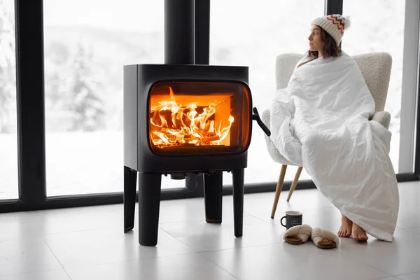 Kobieta w domu z płonącym kominkiem podczas zimy na łonie natury — Zdjęcie stockowe