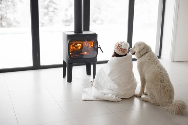 Woman with dog at home with burning fireplace during wintertime — Stock Photo, Image