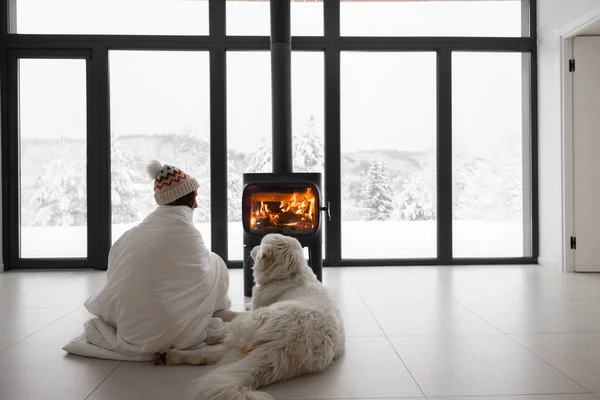 Mulher com cão em casa com lareira em chamas durante o inverno — Fotografia de Stock