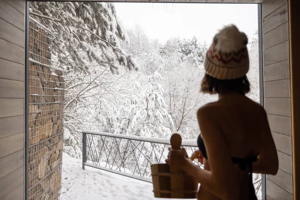 Kobieta odpoczywająca w saunie z widokiem na zaśnieżoną przyrodę — Zdjęcie stockowe