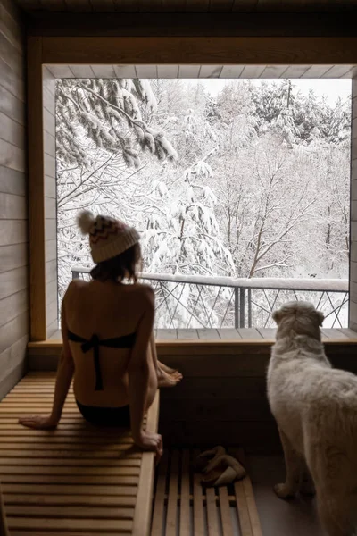 Kobieta odpoczywająca w saunie z widokiem na zaśnieżoną przyrodę — Zdjęcie stockowe