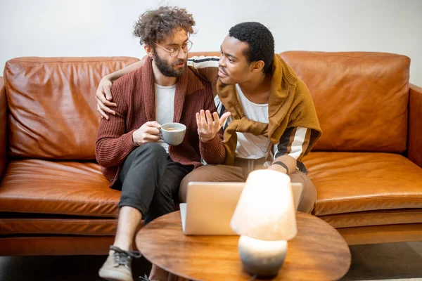 Masculino gay casal falando no um sofá no casa — Fotografia de Stock