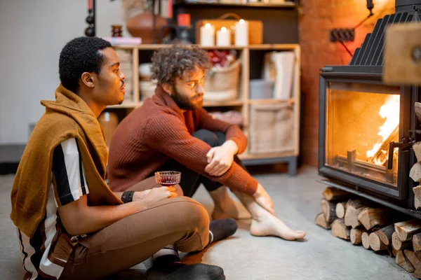 两个男人在舒适的家的壁炉边坐在一起 — 图库照片